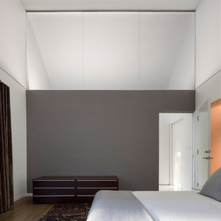 Foto di una grande camera da letto design con pareti grigie, pavimento in legno massello medio e pavimento marrone