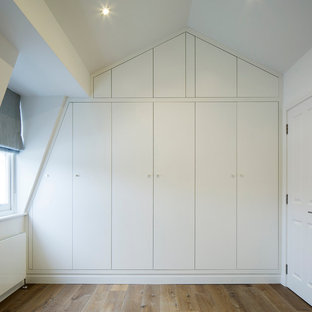 Modelo de habitación de invitados actual, de tamaño medio, con suelo de madera en tonos medios y parades naranjas