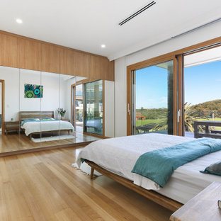 Inspiration for a contemporary bedroom in Sydney with white walls, medium hardwood floors and brown floor.