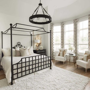 This is an example of a traditional master bedroom in Dallas with white walls, light hardwood flooring, no fireplace and beige floors.