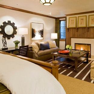 Modelo de dormitorio principal, de estilo americano, grande, con paredes blancas, moqueta, chimenea tradicional, marco de chimenea de piedra y suelo blanco