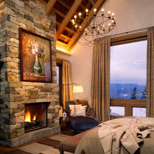 Foto de dormitorio principal, rústico, grande, con chimenea tradicional, marco de chimenea de piedra y paredes blancas
