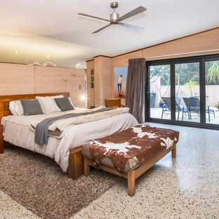 Modelo de dormitorio principal, actual, grande, con suelo de cemento, estufa de leña, marco de chimenea de piedra y suelo multicolor
