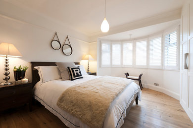 Design ideas for a medium sized contemporary master bedroom in London with white walls and medium hardwood flooring.