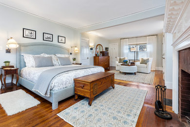 ボストンにある広いトランジショナルスタイルのおしゃれな主寝室 (グレーの壁、濃色無垢フローリング、標準型暖炉、レンガの暖炉まわり、茶色い床)