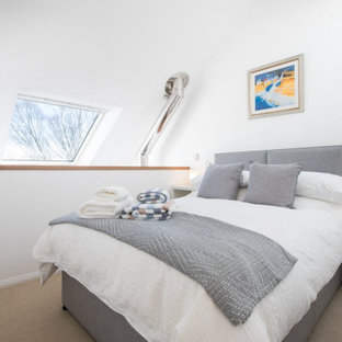 Exemple d'une petit chambre tendance avec un mur blanc, un poêle à bois, un manteau de cheminée en pierre et un sol beige.