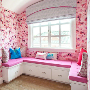 Cette image montre une grand chambre d'amis design avec un mur rose, un sol en bois clair et aucune cheminée.