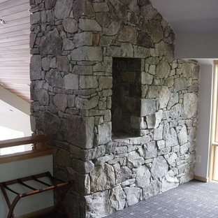 Ejemplo de dormitorio tipo loft, de estilo americano, grande, con paredes blancas, moqueta, chimenea de doble cara y marco de chimenea de piedra