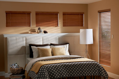 Ejemplo de dormitorio principal tradicional de tamaño medio sin chimenea con parades naranjas y suelo de madera en tonos medios