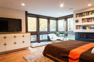 Example of a large minimalist master medium tone wood floor and beige floor bedroom design in Salt Lake City with white walls, a ribbon fireplace and a metal fireplace