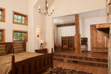 Exempel på ett stort lantligt huvudsovrum, med beige väggar, mellanmörkt trägolv, en standard öppen spis, en spiselkrans i sten och brunt golv