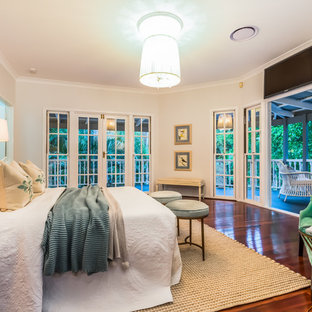 This is an example of a mid-sized beach style master bedroom in Brisbane with beige walls, dark hardwood floors and brown floor.