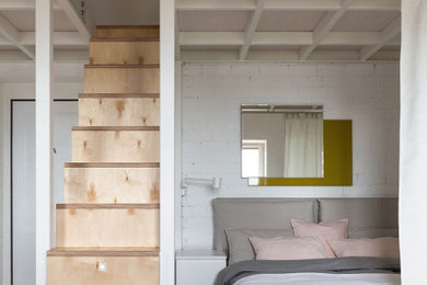 На фото: хозяйская спальня в скандинавском стиле с белыми стенами, полом из ламината, бежевым полом и кирпичными стенами с