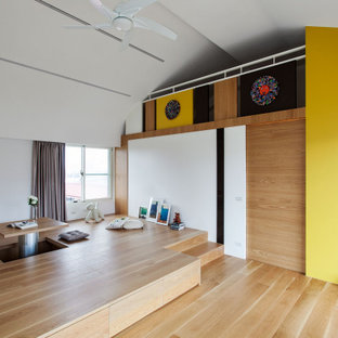 Ejemplo de dormitorio tipo loft, contemporáneo, sin chimenea, con paredes amarillas, suelo de madera clara y suelo amarillo