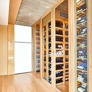 Foto de bodega actual, grande, con suelo de madera clara, botelleros y suelo beige