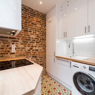 Exemple d'une buanderie méditerranéenne multi-usage avec un évier posé, un placard à porte plane, des portes de placard blanches, un plan de travail en bois, un mur rouge et un sol multicolore.