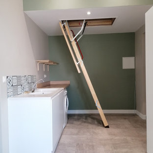 Idéer för att renovera ett stort minimalistiskt beige parallellt beige grovkök, med en undermonterad diskho, luckor med profilerade fronter, vita skåp, träbänkskiva, blått stänkskydd, stänkskydd i cementkakel, gröna väggar, en tvättmaskin och torktumlare bredvid varandra och beiget golv