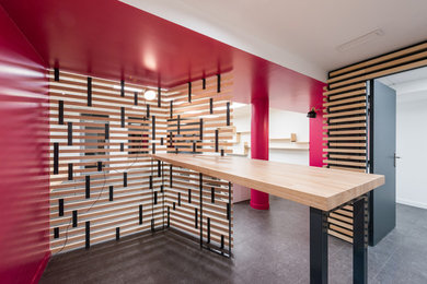 Cette image montre un grand bureau design avec un sol en linoléum, un sol gris, un mur rouge, aucune cheminée et un bureau intégré.