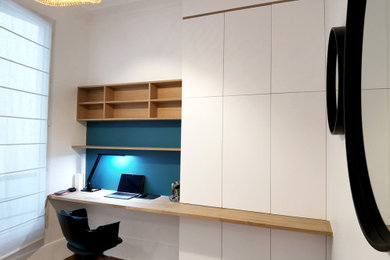 Diseño de despacho actual de tamaño medio con paredes azules, suelo de madera oscura, escritorio independiente y suelo marrón