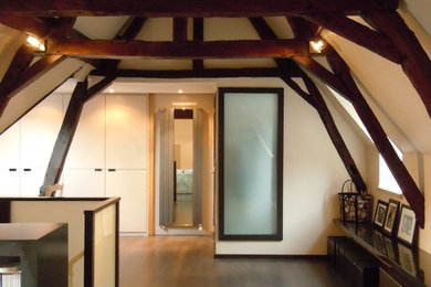Diseño de despacho contemporáneo de tamaño medio con biblioteca, paredes blancas y suelo de madera oscura