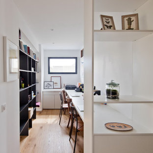 Cette image montre un bureau design de taille moyenne avec un sol en bois clair, un bureau intégré, un mur blanc et un sol marron.
