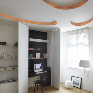 Inspiration för ett stort minimalistiskt hemmabibliotek, med vita väggar, ljust trägolv och ett inbyggt skrivbord