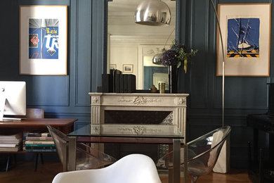 パリにある広いモダンスタイルのおしゃれな書斎 (青い壁、淡色無垢フローリング、標準型暖炉、石材の暖炉まわり、自立型机) の写真