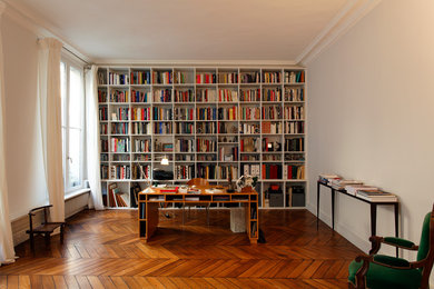 Réalisation d'un grand bureau design avec un sol en bois brun, un bureau indépendant et un mur blanc.