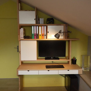 Inredning av ett modernt hemmabibliotek, med gula väggar, ljust trägolv och ett fristående skrivbord