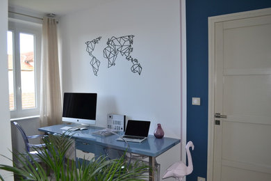 Ejemplo de despacho minimalista con paredes azules, suelo laminado, escritorio empotrado y suelo beige