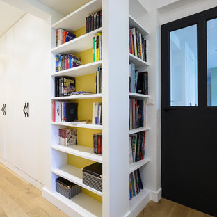 Modern inredning av ett hemmabibliotek, med gula väggar och ljust trägolv