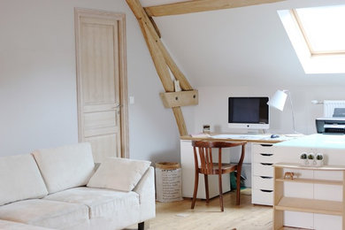 Diseño de despacho nórdico grande sin chimenea con paredes grises, suelo de madera clara, escritorio empotrado y suelo beige