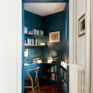 Cette photo montre un petit bureau tendance avec un mur bleu, un sol en bois brun, un bureau intégré et un sol marron.