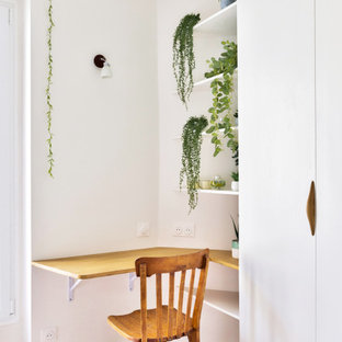 Foto på ett mellanstort minimalistiskt arbetsrum, med vita väggar, ljust trägolv, en spiselkrans i trä och ett inbyggt skrivbord