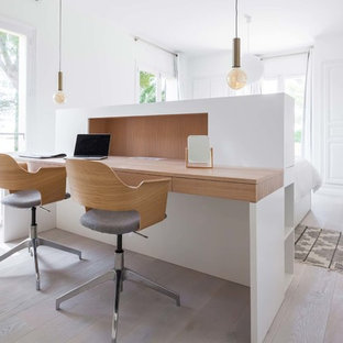 Cette photo montre un grand bureau scandinave avec un mur blanc, un sol en bois clair, un bureau intégré et un sol beige.