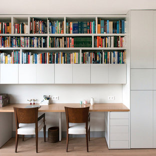 Cette image montre un grand bureau nordique avec un mur blanc, un sol en bois clair et un bureau intégré.