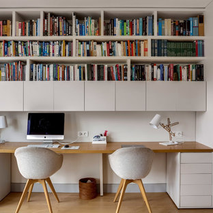 Cette photo montre un bureau scandinave avec un mur blanc, un sol en bois brun, un bureau intégré et un sol marron.