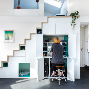 Immagine di un piccolo studio nordico con libreria, pareti bianche, pavimento in vinile, stufa a legna e pavimento grigio