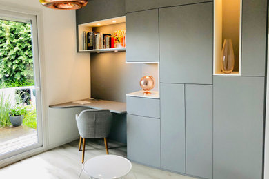 Cette photo montre un bureau tendance de taille moyenne avec une bibliothèque ou un coin lecture, un mur gris, un sol en vinyl, aucune cheminée, un bureau indépendant et un sol beige.