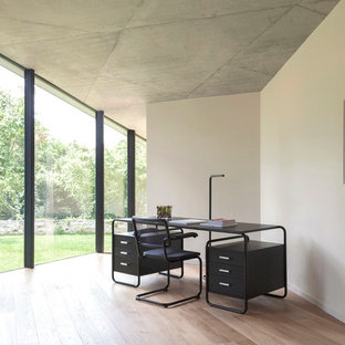 Aménagement d'un grand bureau contemporain avec un bureau indépendant, un mur blanc, un sol en bois clair, aucune cheminée et un sol beige.