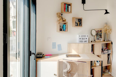 Modernes Arbeitszimmer mit Arbeitsplatz, weißer Wandfarbe, hellem Holzboden, freistehendem Schreibtisch und beigem Boden in Paris