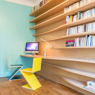 Modern inredning av ett mellanstort hemmabibliotek, med blå väggar, mellanmörkt trägolv och ett inbyggt skrivbord
