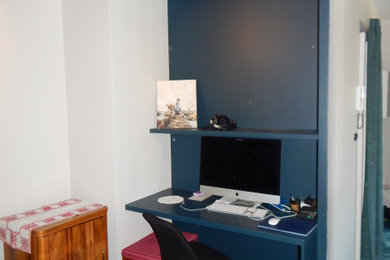 Aménagement d'un petit bureau rétro avec un mur bleu, moquette, un bureau intégré et un sol bleu.