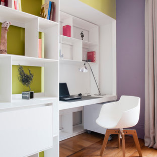 Réalisation d'un bureau design avec un sol en bois brun, un bureau intégré et un mur multicolore.