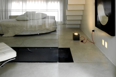 Ispirazione per una camera matrimoniale design con pavimento in cemento e pavimento bianco