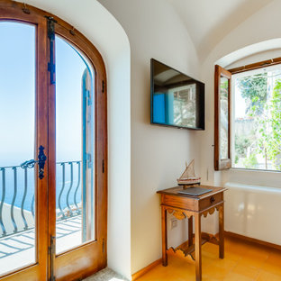 Imagen de dormitorio principal y abovedado, mediterráneo, de tamaño medio, con paredes blancas, suelo de baldosas de cerámica y suelo amarillo