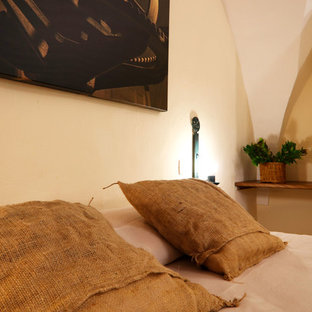 Modelo de dormitorio principal, rural, de tamaño medio, con paredes blancas, suelo de piedra caliza y suelo beige