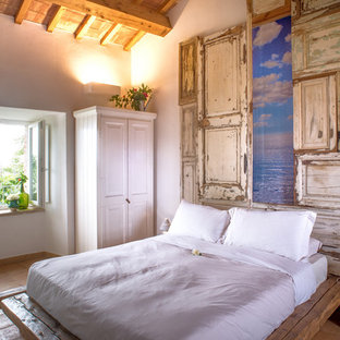 Esempio di una camera da letto mediterranea con pareti bianche, pavimento in terracotta e pavimento marrone