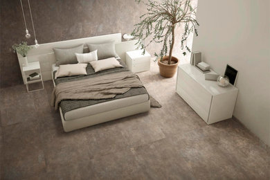 Immagine di una camera da letto minimalista con pareti grigie, pavimento in gres porcellanato e pavimento grigio
