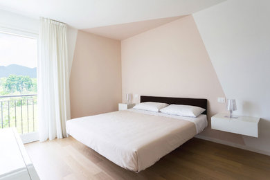 Immagine di una camera matrimoniale minimal con parquet chiaro, pareti multicolore e pavimento beige